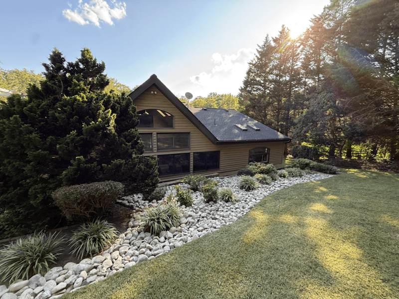 Finished river rock landscaping bed beside a home